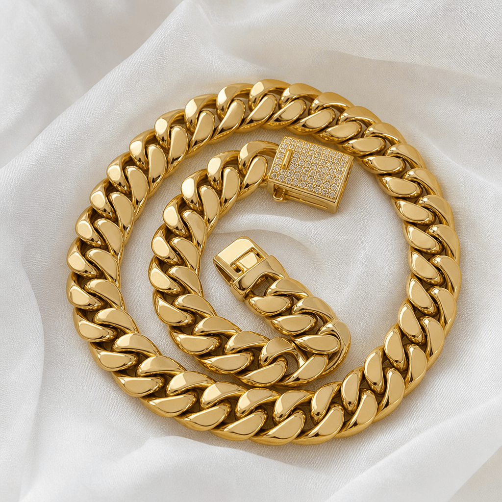 Solid gold Miami Cuban link chain coiled on white fabric, Jade Gold NYC.